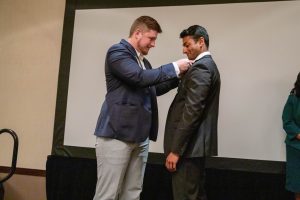 A graduating student is pinned at the 2022 Spring Networking Dinner